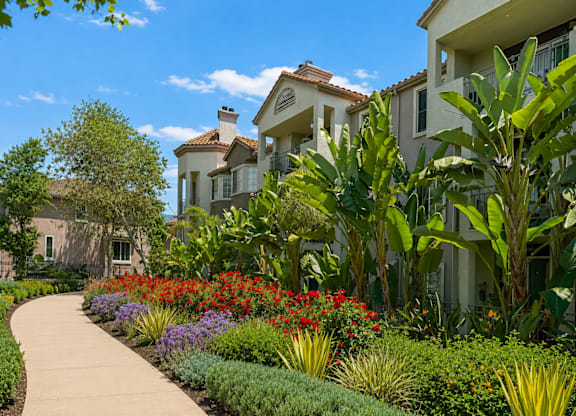 Curved walkway with red and purple floral landscaping at River Front Apartments, San Diego, CA 92108