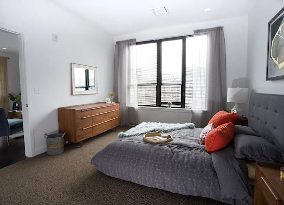 A bedroom with a large bed and a window with blinds.
