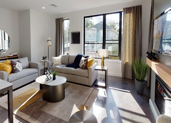 A modern living room with a grey sofa, a coffee table, and a large mirror.