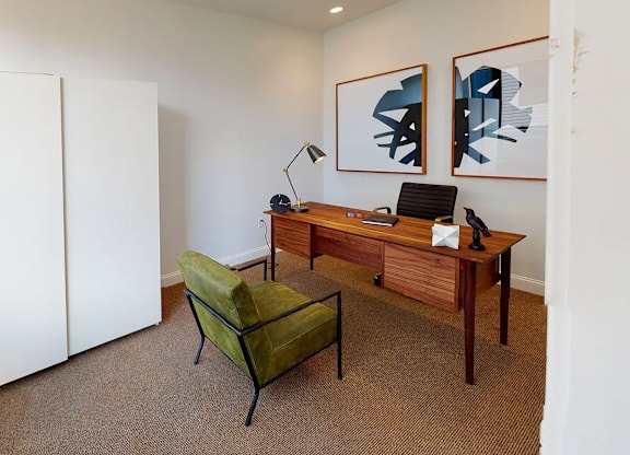 A room with a desk, chair, and two pictures on the wall.