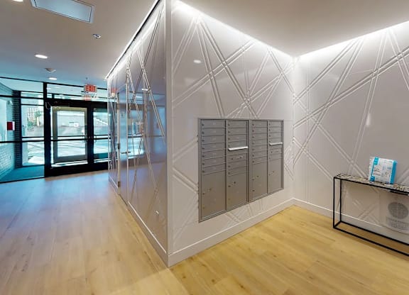 A white reception area with a black railing and a white wall with a geometric pattern.