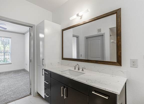 A bathroom with a sink, mirror, and black cabinets.