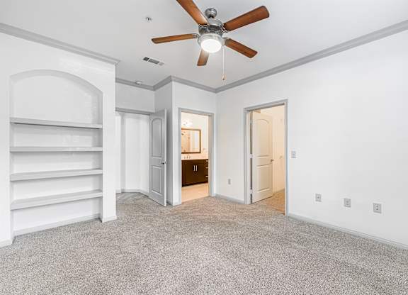 A room with a ceiling fan and carpeted floor.