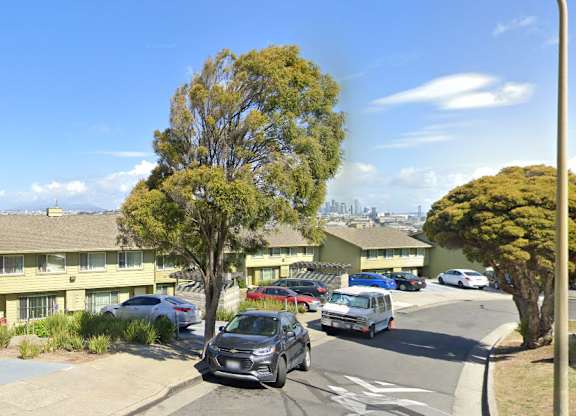 A street view of a residential area with cars parked on the side of the road.