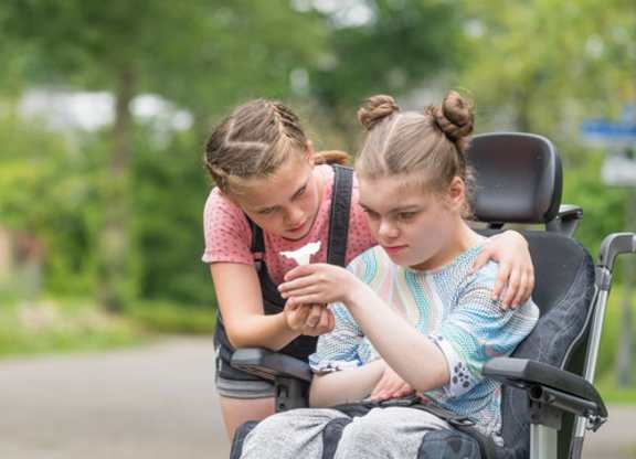 Disabled Child looking at flower with another child