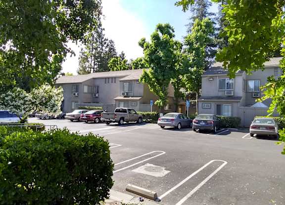 Colonial Farms Apartments - parking lot in front with apartment buildings in the background, trees