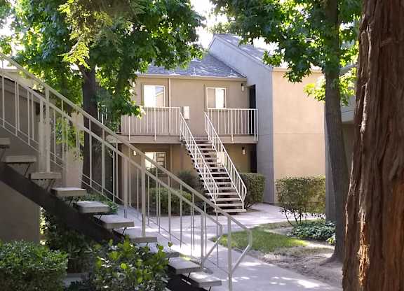 Colonial Farms Apartments - concrete walkway up to stairs to apartments with tree in foreground