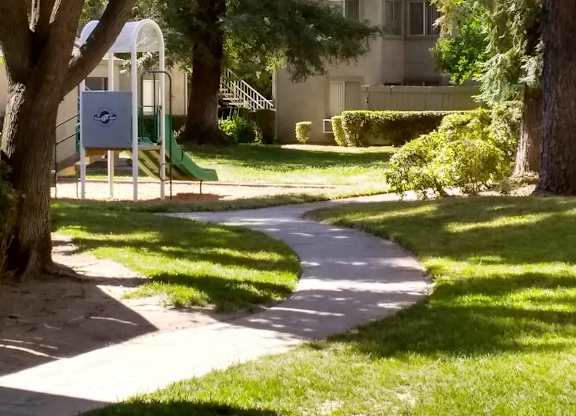 Colonial Farms Apartments - concrete walkway with grass and trees on either side