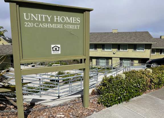 A sign for Unity Homes stands in front of a building.