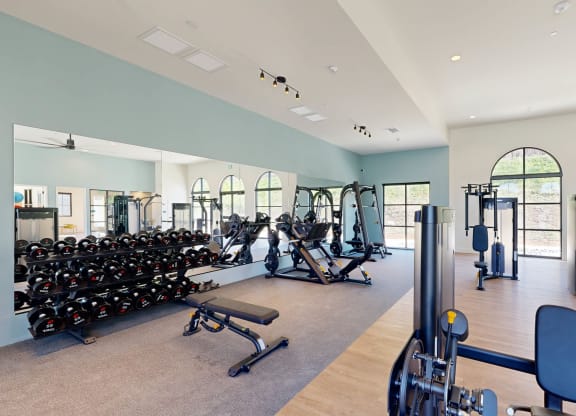 a gym with cardio equipment and weights in a building with windows at The Villas at Anacapa Canyon, Camarillo, California