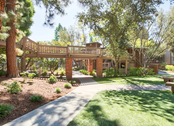 a walkway leading to a building with a wooden deck at The Meadows Apartments, California