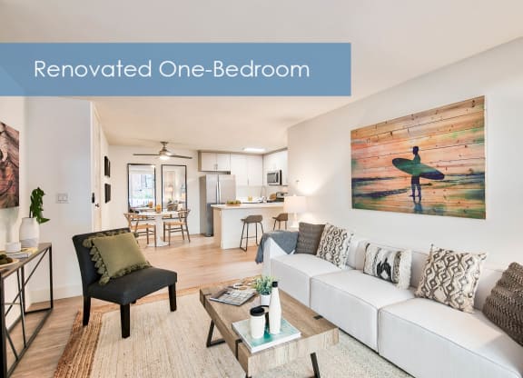 a renovated one bedroom living room with a white couch and a surfboard at The Meadows Apartments, Culver City , CA 90230