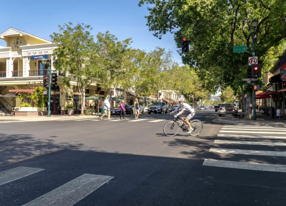 a man riding a bike down a city street  at Pleasanton Place, Pleasanton, CA, 94566