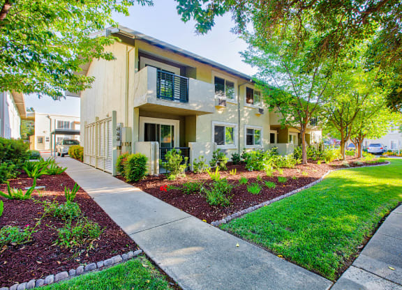 a sidewalk in front of a building with grass and trees  at Pleasanton Place, California, 94566