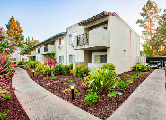 a sidewalk in front of a building with plants and trees at Pleasanton Place, Pleasanton, CA, 94566