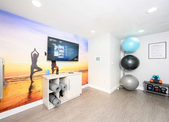 a yoga room with a large screen tv and a yoga ball at Sendero Huntington Beach, Huntington Beach
