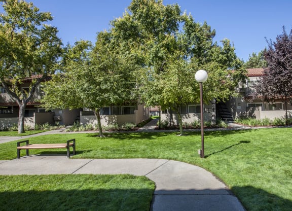 a park with grass and trees in front of a building at Valley Plaza Villages, Pleasanton, CA