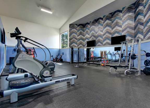A gym with a rowing machine and a wall of mirrors.
