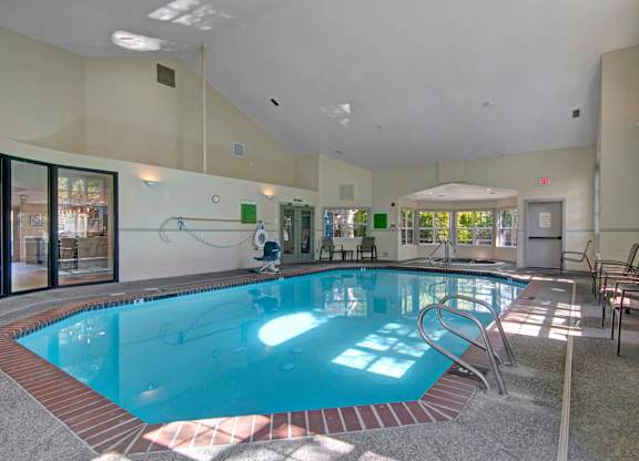 A large indoor swimming pool with a sunny day outside.