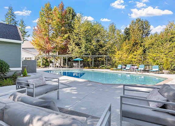 A pool surrounded by trees and a house.