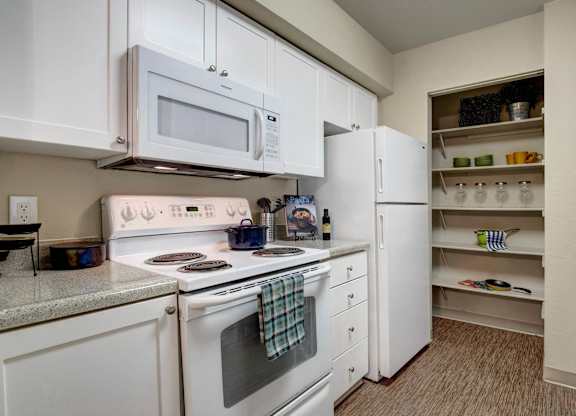 Bright kitchen with white cabinetry, granite-style counters, and a pantry.