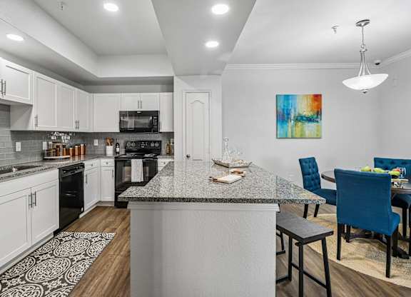 A kitchen with a large island and a dining area with blue chairs.