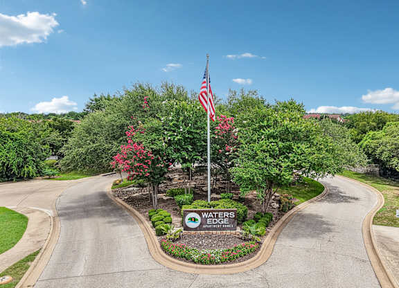 A sign in front of a road reads "Waters Edge.".