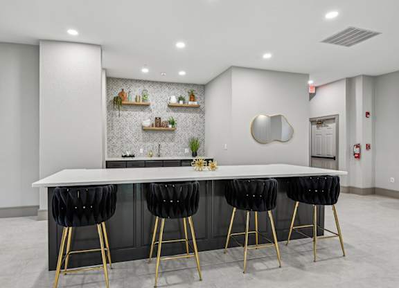 A modern kitchen with a white countertop and black bar stools.