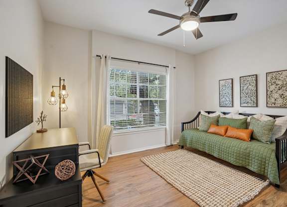 A room with a green sofa and a fan on the ceiling.