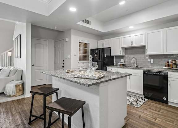 A kitchen with a granite countertop and white cabinets.