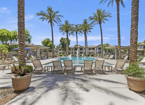 a swimming pool with chaise lounge chairs and palm trees at Adiamo Palm Valley, Goodyear, AZ