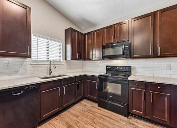A kitchen with dark wood cabinets and black appliances.