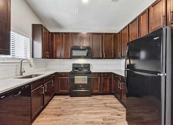 A kitchen with dark wood cabinets and a black refrigerator.