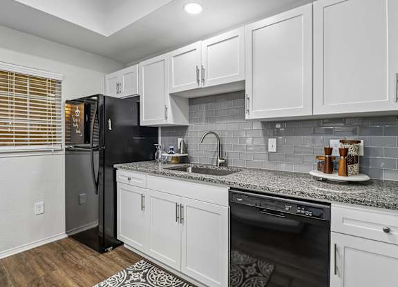 A kitchen with white cabinets and a black refrigerator.