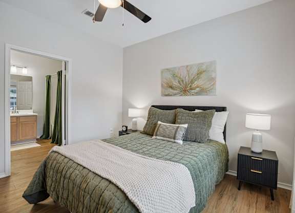 A bedroom with a bed, nightstand, and a ceiling fan.