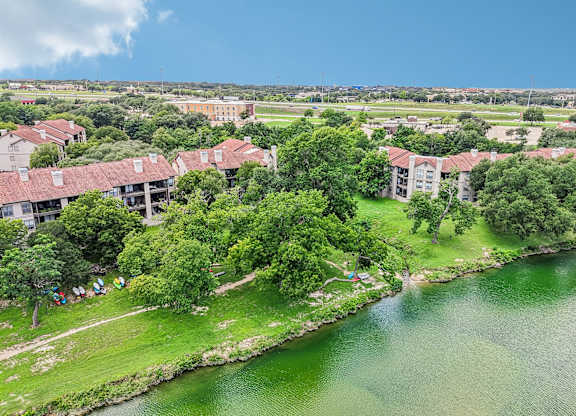 A large body of water is surrounded by greenery and buildings.