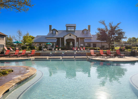 a large pool with chairs and a house in the background at The Fairways at Star Ranch, Hutto