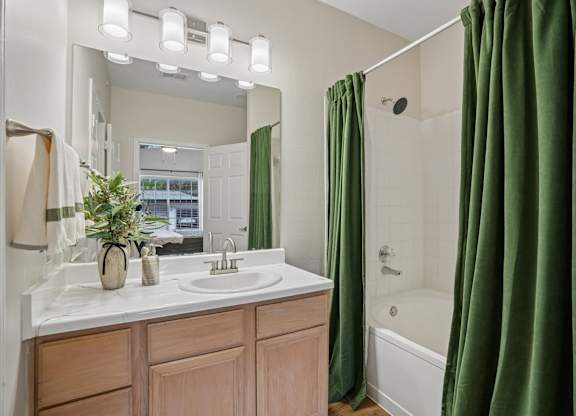 A bathroom with a white sink and green curtains.