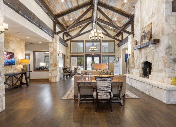 a dining room with a table and chairs in front of a stone fireplace at Lakeline East Apartments, Cedar Park