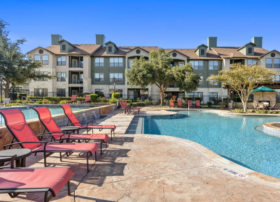 commons pool with chairs and an apartment building at The Fairways at Star Ranch, Hutto