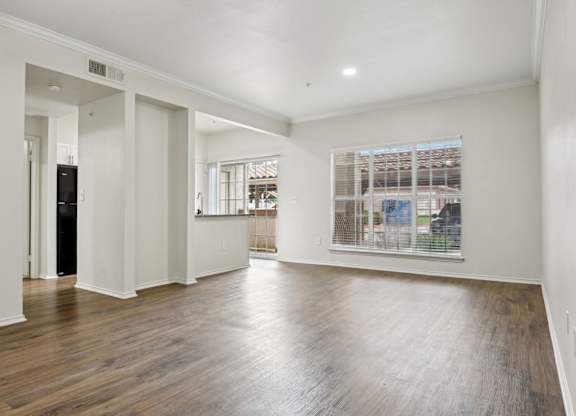A spacious room with wooden floors and white walls.