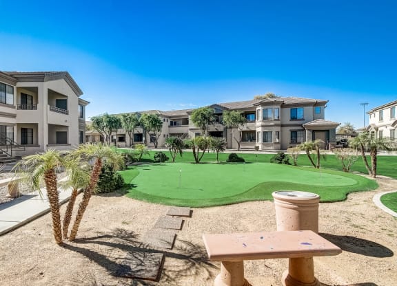 a putting green in the middle of an apartment complex with buildings  at Adiamo Palm Valley, Goodyear, AZ