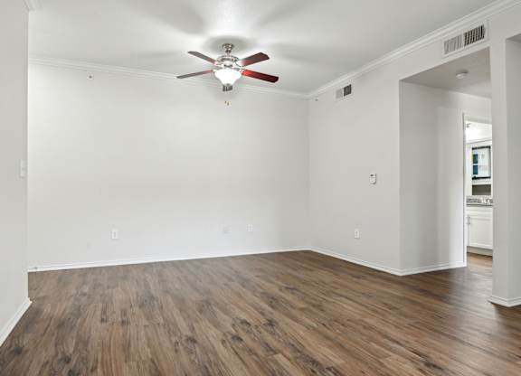 A room with a ceiling fan and wooden flooring.