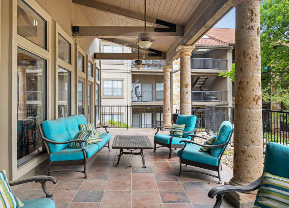 A covered patio with blue chairs and a coffee table at Waters Edge Apartment Homes, Georgetown