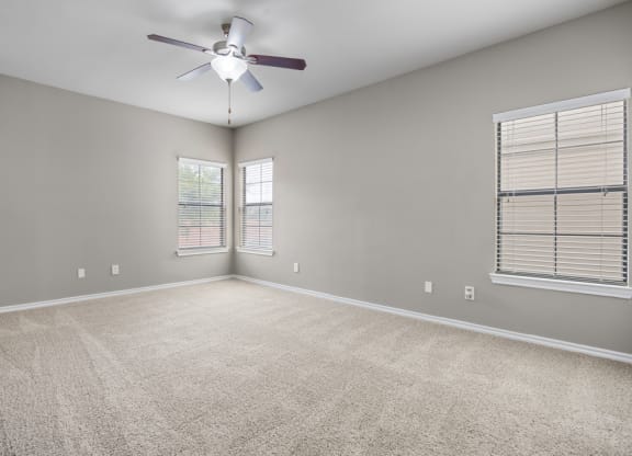 An empty room with a ceiling fan and two windows at Waters Edge Apartment Homes, Georgetown, 78626