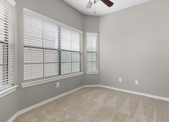 A bedroom with two large windows and a ceiling fan at Waters Edge Apartment Homes, Georgetown, TX