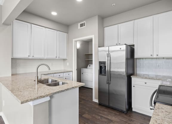 A kitchen with white cabinets and a stainless steel refrigerator at Waters Edge Apartment Homes, Georgetown, TX, 78626