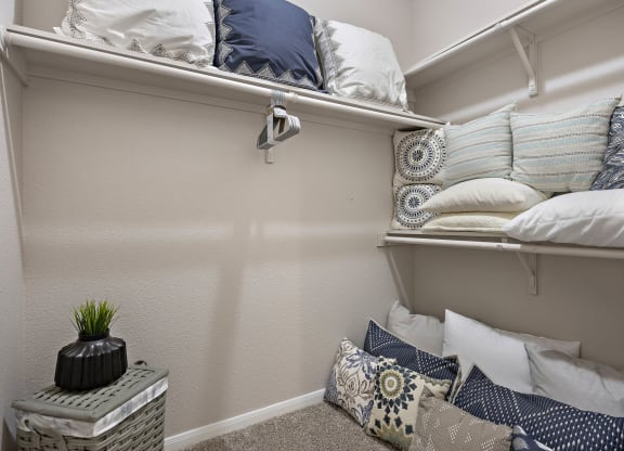 a walk in closet in a bedroom with pillows on the floor and a shelf with pill at Artisan Apartments & Shops, Austin, Texas