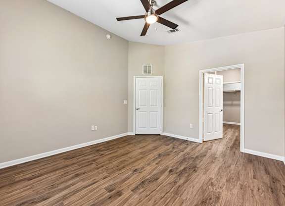 A room with a ceiling fan and wooden flooring.
