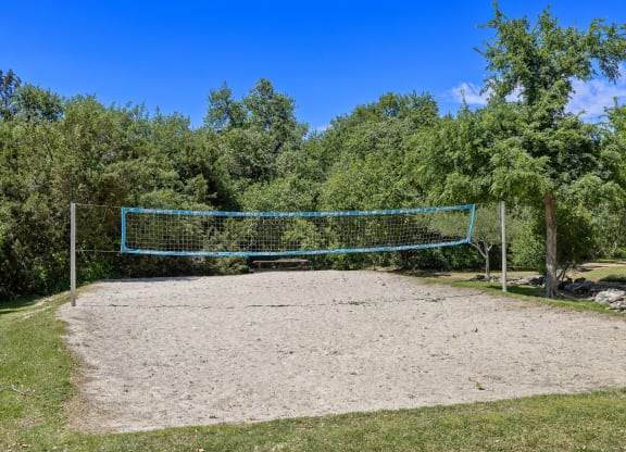 the volleyball court is located in front of the trees at Lakeline East Apartments, Cedar Park